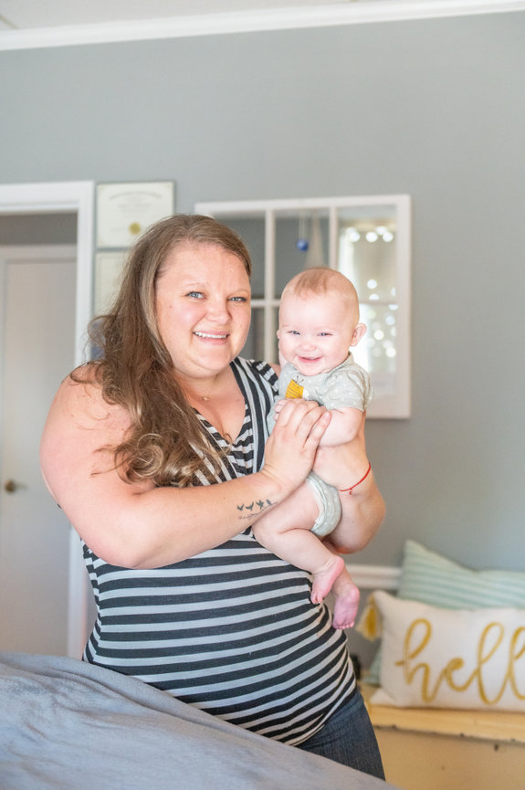 Deandra holding a baby, smiling.